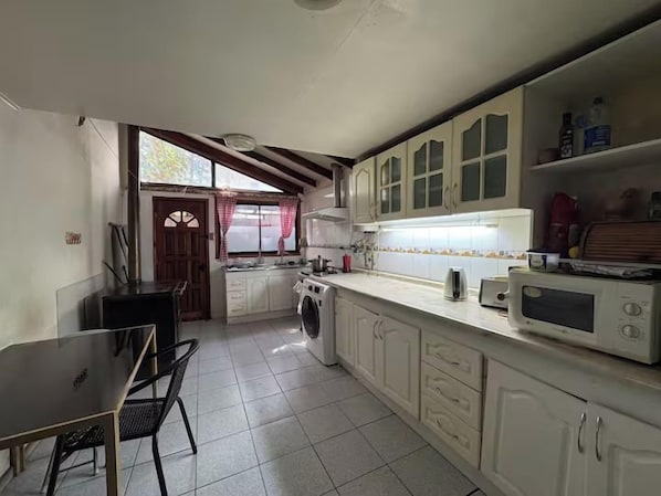 A compact kitchen with a dining area, a washing machine, and a microwave.