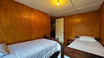 A room with two wooden bunk beds, a door, and a light fixture on the ceiling.