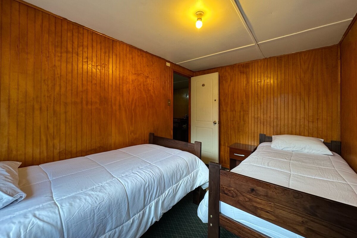 A room with two wooden bunk beds, a door, and a light fixture on the ceiling.