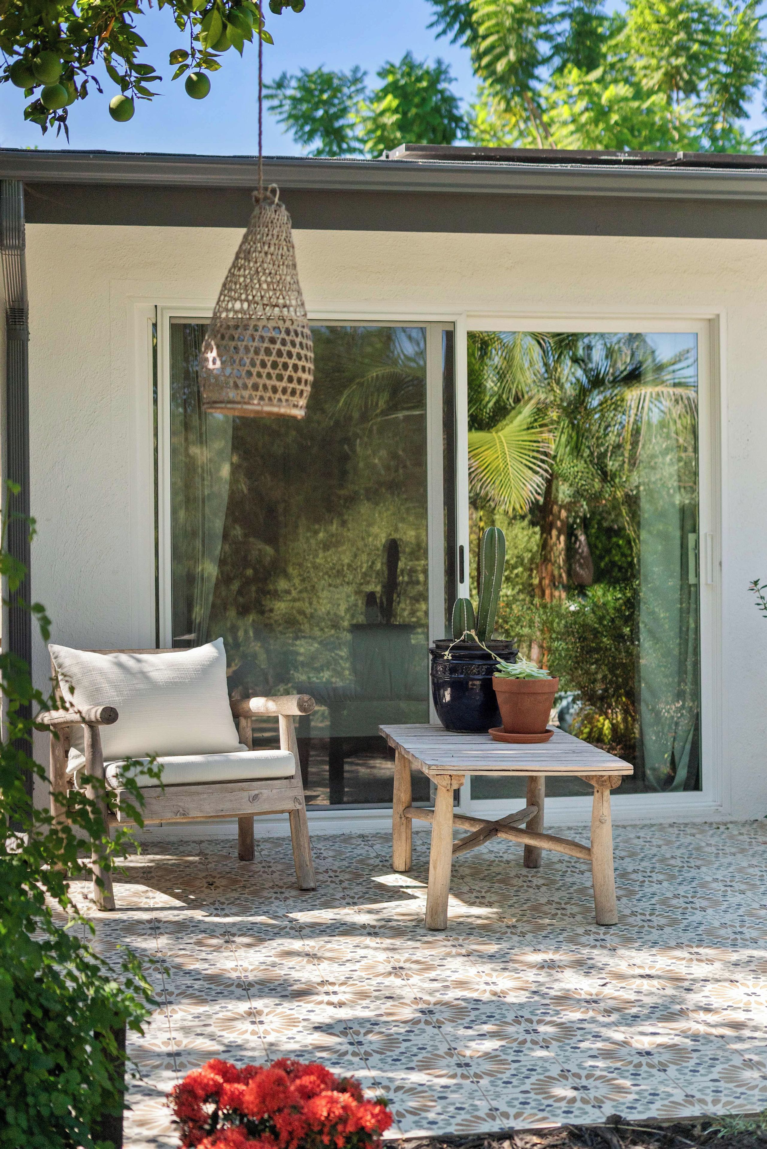 A patio with a wooden chair and table, a hanging light fixture, and a potted plant.