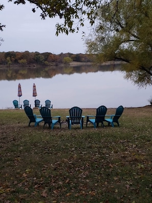 A lakeside setting with outdoor seating and umbrellas. - Lakefront Paradise 4 king bedrooms, Hot Tub & Private Beach ,fire pit sleeps 12 (Little Elm)