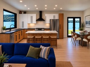 A modern kitchen with a central island, stainless steel appliances, and a view of a lake through large windows. - Lakefront Paradise 4 king bedrooms, Hot Tub & Private Beach ,fire pit sleeps 12 (Little Elm)
