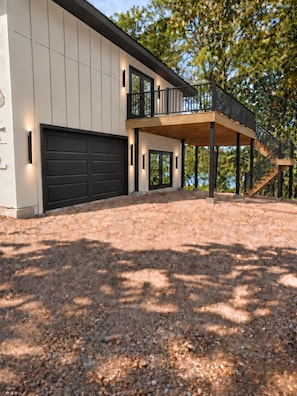 A modern house with a garage, a covered porch, and a staircase leading to a deck. - Lakefront Paradise 4 king bedrooms, Hot Tub & Private Beach ,fire pit sleeps 12 (Little Elm)