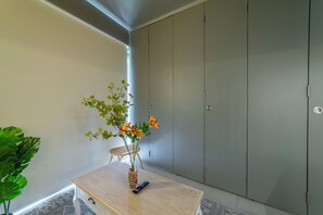 Una habitación con una mesa de madera, un jarrón con flores, un control remoto y un armario gris.