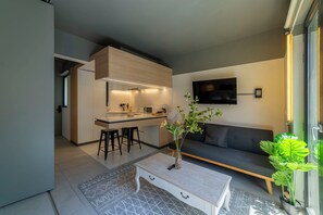 Eine moderne Küche mit Barbereich, einer Sitzecke inklusive Sofa und Couchtisch sowie einem großen Fenster mit Aussicht.