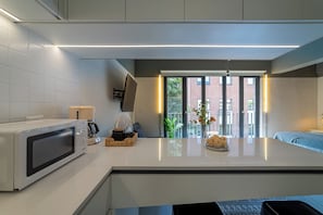 Eine moderne Küche mit Mikrowelle, Wasserkocher und einer kleinen Essecke mit Tisch und Stühlen.