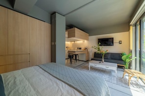 Ein modernes Schlafzimmer mit Bett, Sofa, Essbereich und Fernseher.