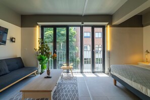 Un dormitorio moderno con cama, sofá, mesa y una planta en maceta.