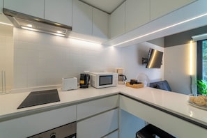 Eine moderne Küche mit weißen Schränken, einer eingebauten Mikrowelle, einem Toaster und einer Kaffeemaschine.
