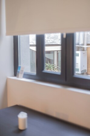 A window with a view of a building and some plants outside. - Bright 1-bedroom apartment + large window · Selected (H16) (Providencia)