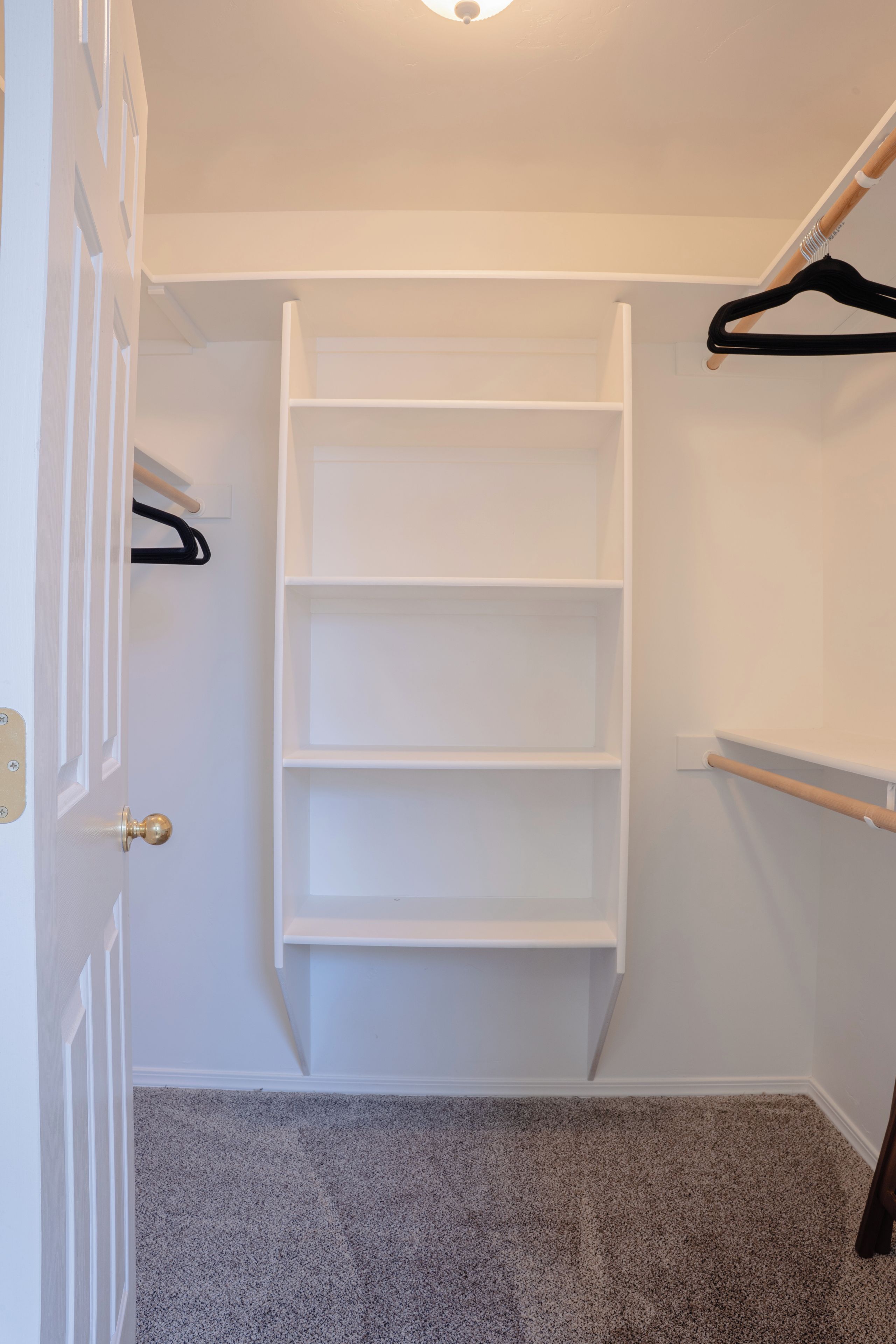 Un vestidor con estanterías blancas y una barra para colgar ropa.