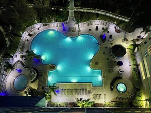 An aerial view of a hotel pool area with a large central pool, surrounding lounge areas, and a small circular pool. - Balcony Lake Views | Pool, Gym, WiFi & Parking (Orlando)