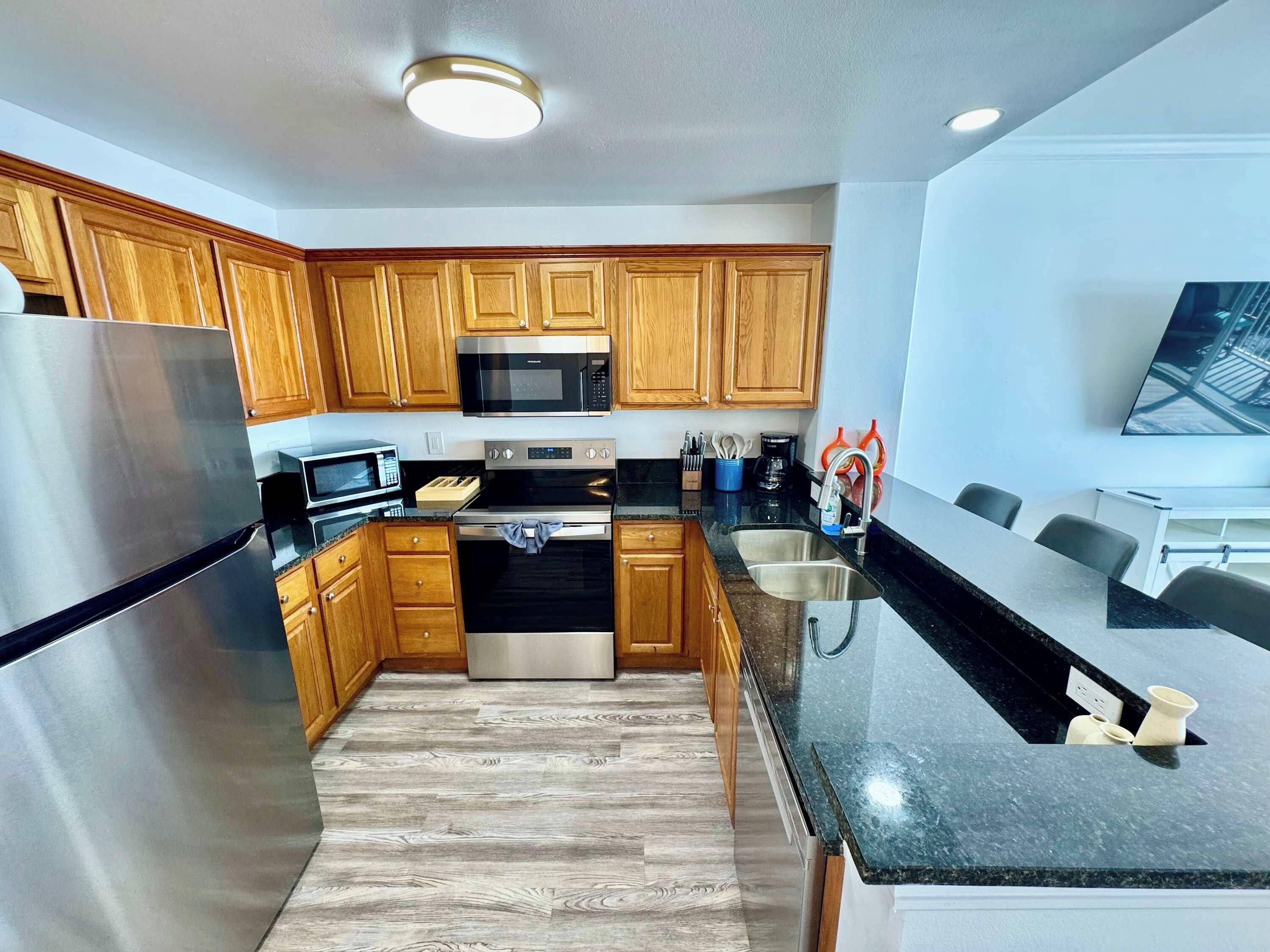 A modern kitchen with wooden cabinets, stainless steel appliances, and a black granite countertop.