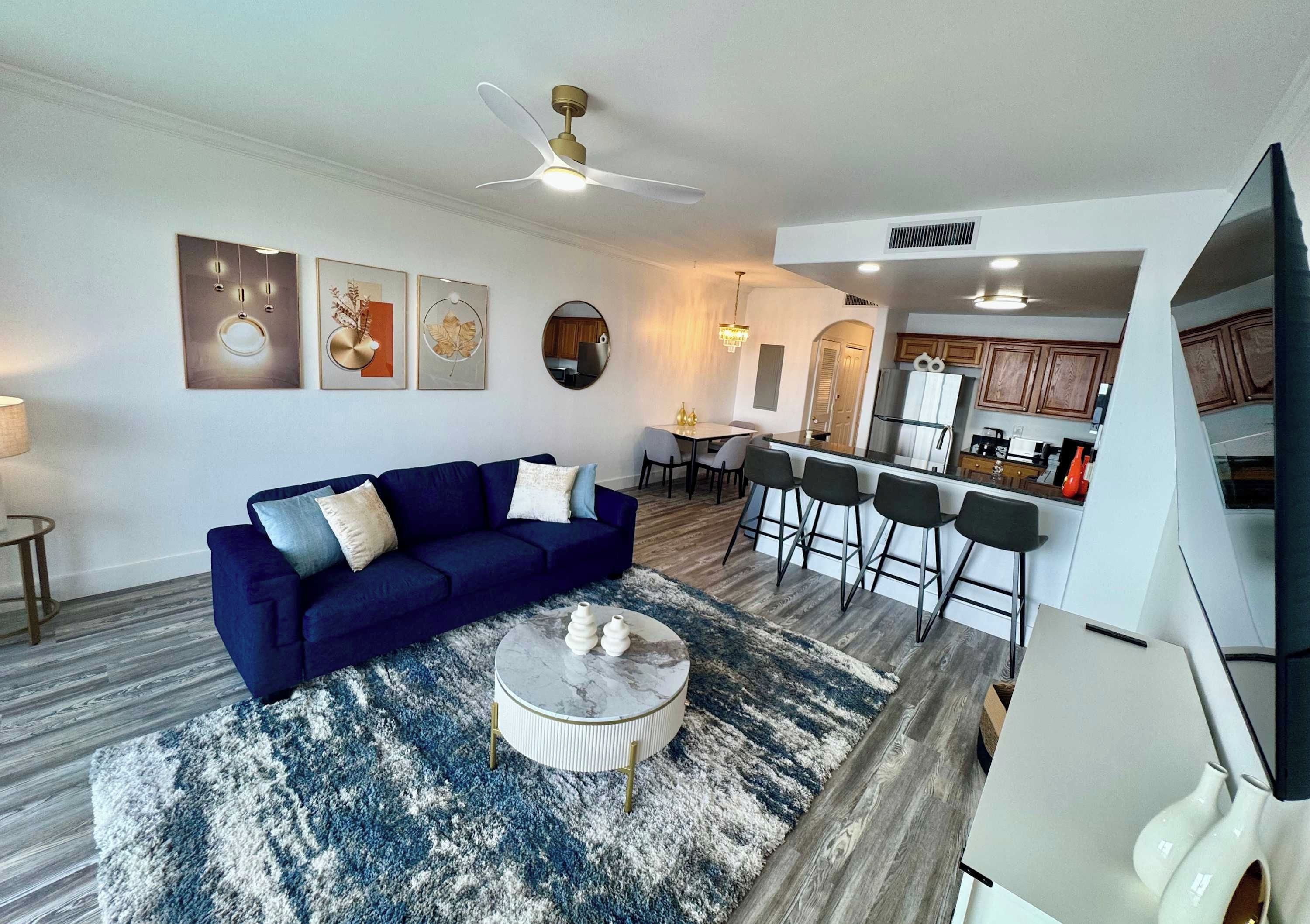 A modern living room with a blue sofa, a coffee table, and a ceiling fan.