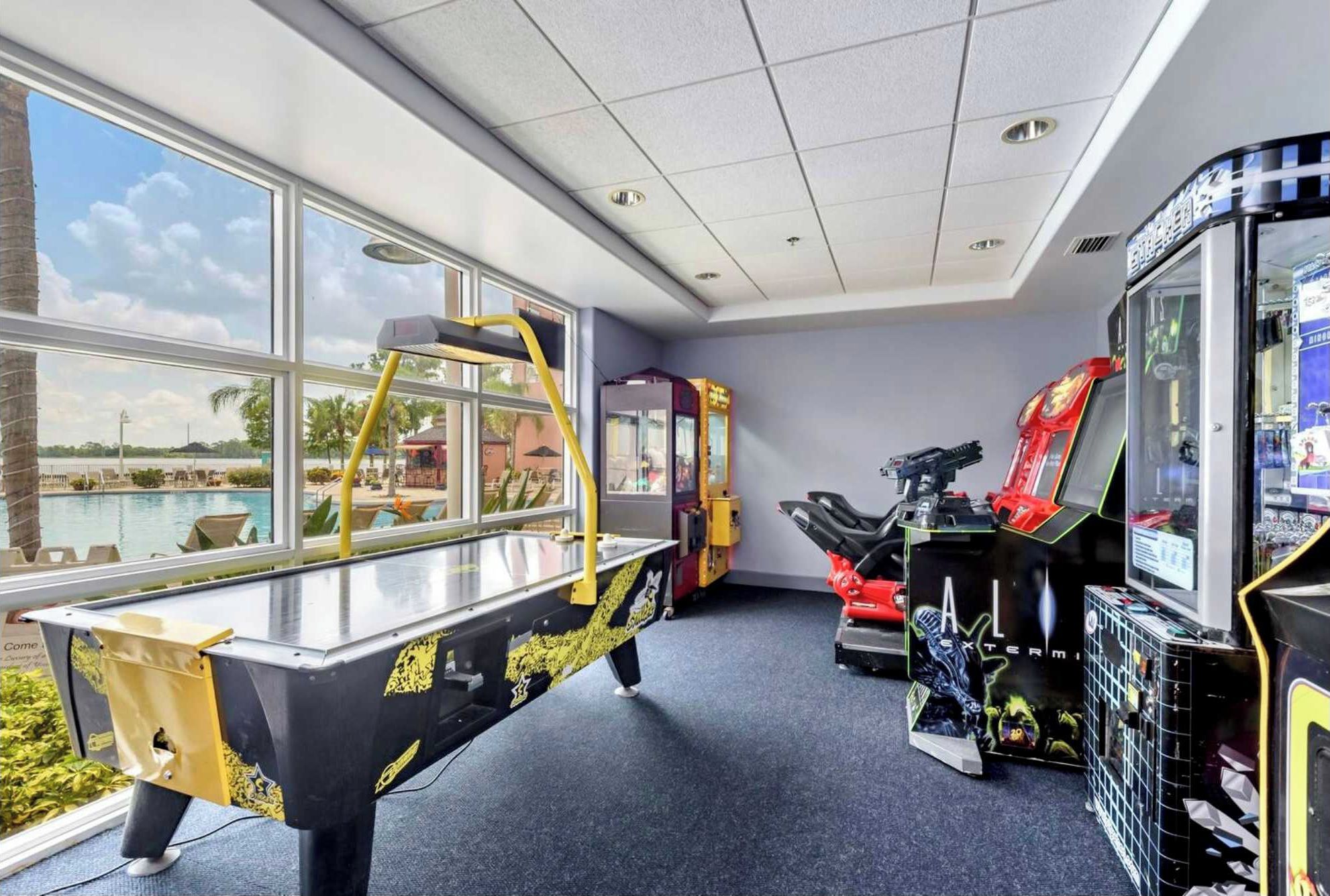 A room with arcade games, a pool view, and a large window.