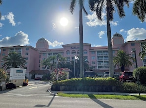 A hotel with a pink facade, palm trees, and a clear sky. - Oceanfront 2 Bedroom Unit for 6 people at Palm Beach Shores Resort Singer Island (Palm Beach Shores)