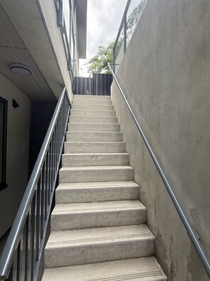 Escadaria de concreto com corrimãos de metal que dá acesso a um andar superior.