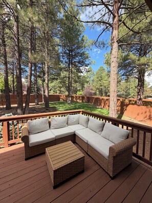 A wooden deck with a wicker sectional sofa and a small table. - Family-Friendly, Pet-Friendly House With Spacious Fenced Backyard In Flagstaff (Flagstaff)