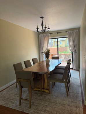 A dining area with a wooden table and chairs, a chandelier, and a view of a backyard through a sliding glass door. - Family-Friendly, Pet-Friendly House With Spacious Fenced Backyard In Flagstaff (Flagstaff)