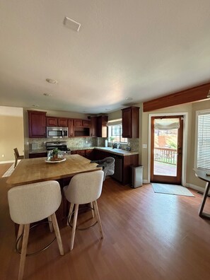 A kitchen with wooden cabinets, a granite countertop, a dining table with chairs, and a view of the outdoors through a door. - Family-Friendly, Pet-Friendly House With Spacious Fenced Backyard In Flagstaff (Flagstaff)