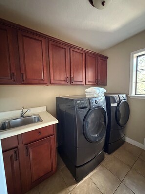 A laundry room with two front-loading washers, a sink, and wooden cabinets. - Family-Friendly, Pet-Friendly House With Spacious Fenced Backyard In Flagstaff (Flagstaff)