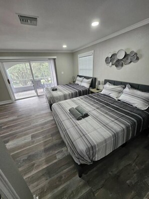 A hotel room with two beds, a large window, and a view of greenery outside. - Beautiful Historical 6 Bdrm Lakefront Pool Home (Auburndale)