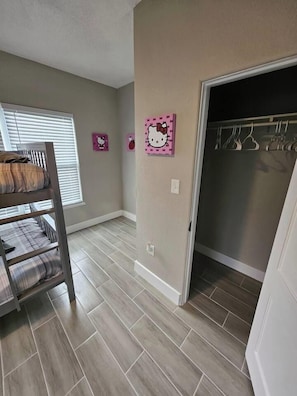 A room with a bunk bed, a closet with hanging clothes, and a door leading to another room. - Beautiful Historical 6 Bdrm Lakefront Pool Home (Auburndale)