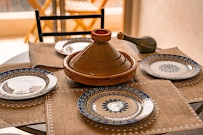 A traditional Moroccan setting with a tagine, plates, and a woven tablecloth. - Moroccan Style Apartment in Gueliz – Near Carré Eden Mall (Marrakesh)