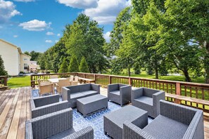 A deck with outdoor furniture and a view of a grassy area and trees. - The Westfield Retreat | 7 Bedrooms • 30+ Day Stays (Westfield)