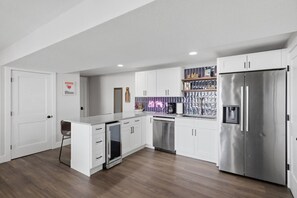 A modern kitchen with white cabinetry, a stainless steel refrigerator, a dishwasher, and a built-in oven. - Booje Bay : Luxury, Lakefront, Hot Tub! (Sunrise Beach)
