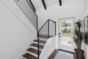 A staircase with a modern design, a door with a glass panel, and a potted plant. - Booje Bay : Luxury, Lakefront, Hot Tub! (Sunrise Beach)
