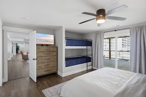A bedroom with a bed, a ceiling fan, a dresser, and bunk beds. - Booje Bay : Luxury, Lakefront, Hot Tub! (Sunrise Beach)