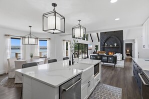 A modern kitchen with a central island, pendant lighting, and a fireplace. - Booje Bay : Luxury, Lakefront, Hot Tub! (Sunrise Beach)