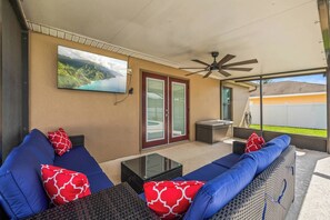 An outdoor patio with a sofa set, a ceiling fan, a television mounted on the wall, and a view of a mountainous landscape. - 3BR Lakeland Getaway | Pool & AC Game Room (Lakeland)
