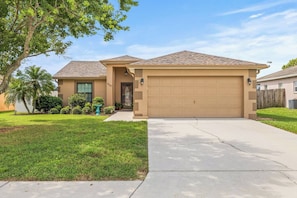 A residential house with a garage, a driveway, and a well-maintained lawn. - 3BR Lakeland Getaway | Pool & AC Game Room (Lakeland)