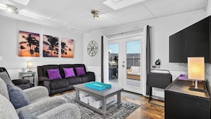 A modern living room with a sofa, coffee table, and artwork on the wall. - Bradley Beach House by Avantstay Walk to the Beach Hot Tub + Game Room & BBQ Deck (Hilton Head Island)