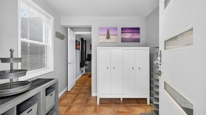 A narrow hallway with a white door, a window with blinds, and a tiled floor. - Bradley Beach House by Avantstay Walk to the Beach Hot Tub + Game Room & BBQ Deck (Hilton Head Island)