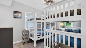 A room with bunk beds, a small table, and a chair. - Bradley Beach House by Avantstay Walk to the Beach Hot Tub + Game Room & BBQ Deck (Hilton Head Island)