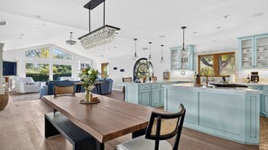 A spacious kitchen with a large island, modern pendant lighting, and a view of the outdoors. - Vino Vista Villa by Avantstay Pool + Hot Tub Fire Pit + Hammock Hilltop Views Near Downtown (Paso Robles)