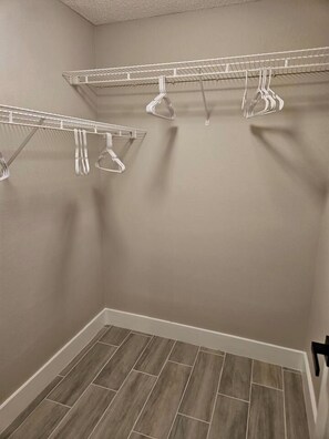 A closet with two wire shelves and a hanging rod, wooden flooring, and a door with a black handle. - Spacious Lakeland 4BR | Pool & AC Game Room (Lakeland)
