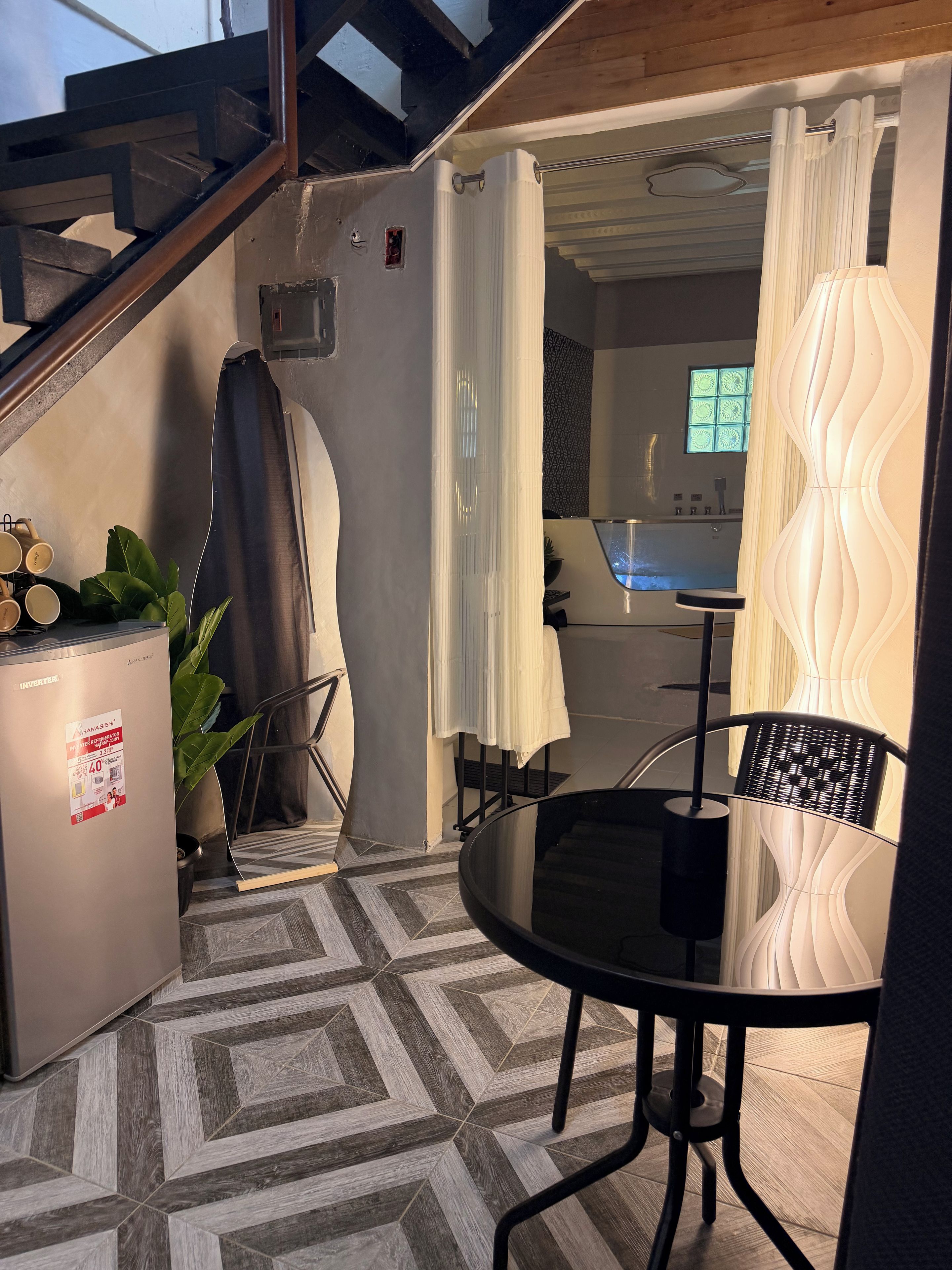 A modern kitchen with a built-in dishwasher, a dining area with a round table and chairs, and a staircase leading to an upper level.