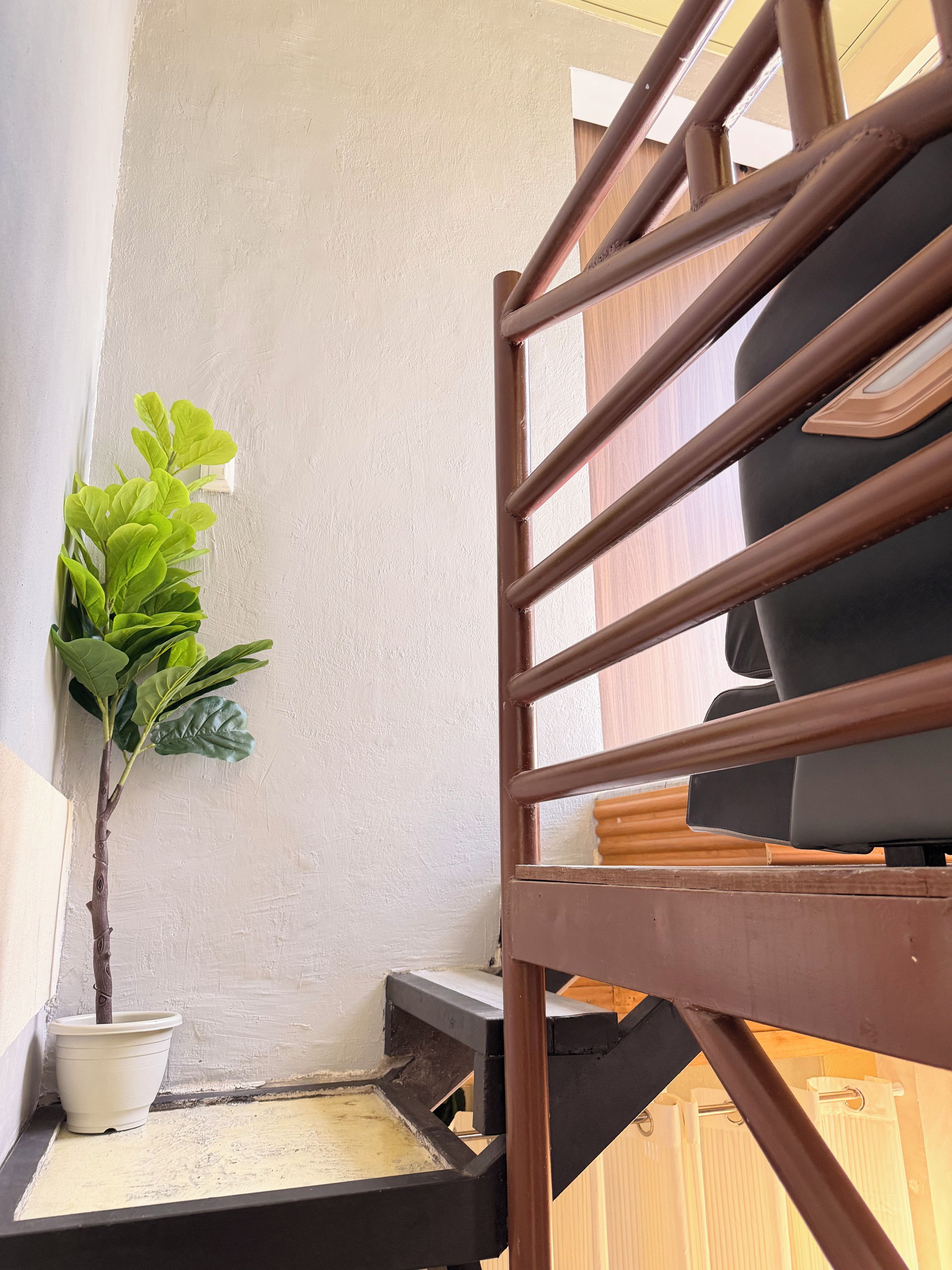 A staircase with a handrail, a potted plant, and a small table with a cushion.