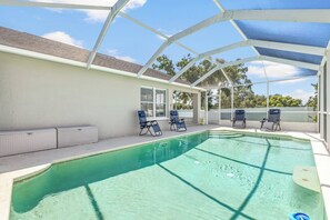 A covered outdoor swimming pool with lounge chairs and a white exterior wall. - Lakeland 3BR | Pool, AC Gameroom & HUGE Yard (Lakeland)
