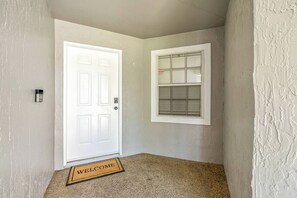 A hallway with a white door, a window with blinds, and a welcome mat. - Lakeland 3BR | Pool, AC Gameroom & HUGE Yard (Lakeland)