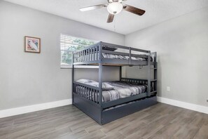 A bunk bed with a ceiling fan, a window with blinds, and a framed picture on the wall. - Private Pool • Sleeps 16 • Huge Yard • AC GameRoom (Lakeland)