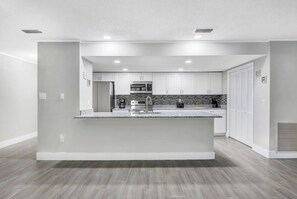 A modern kitchen with white cabinetry, a granite countertop, and stainless steel appliances. - Private Pool • Sleeps 16 • Huge Yard • AC GameRoom (Lakeland)