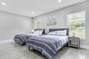 Une chambre avec deux lits, une table de chevet avec une lampe et une fenêtre avec des stores.