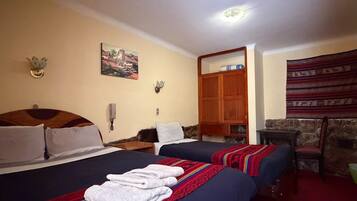 Camera d'albergo con due letti, un armadio in legno, un tavolino, una sedia e un quadro appeso al muro.