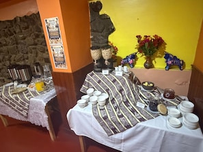 Montaje de un bufé de desayuno con una pared de piedra, una estatua y una pared amarilla al fondo.