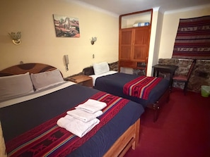 A hotel room with two beds, a wooden wardrobe, a painting on the wall, and a stone wall. - HOTEL HUAYNA HOUSE INN (Cusco)